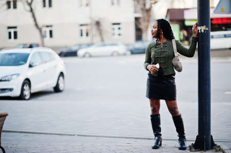 Stylish fashionable african american women in green sweater and black skirt posed outdoor with mobile phone.の写真素材