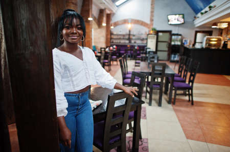 Stylish african american women in white blouse and blue jeans posed at cafe.の写真素材