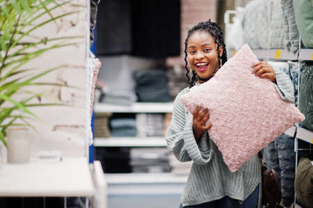 African woman choosing pillow for her apartment in a modern home furnishings store.