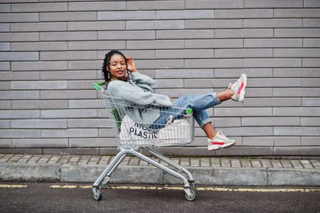 African woman sitting at shopping cart trolley posed outdoor market.の写真素材