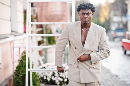 Stylish afro man in beige old school suit. Fashionable young African male in casual jacket on bare...
