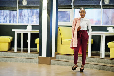 Charming african american woman in formal wear posing at restaurant.