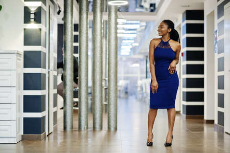 Charming african american woman in blue dress posing at restaurant.の写真素材