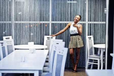 Charming african american woman in leopard skirt posing at restaurant.の写真素材