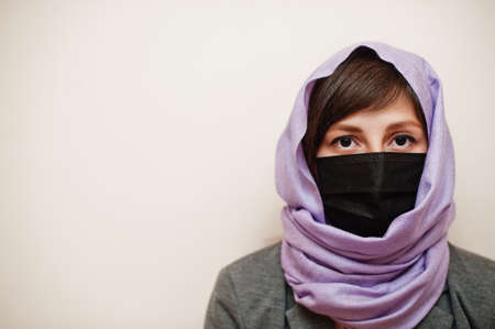 Portrait of young muslim woman wearing formal wear, protect face mask and hijab head scarf against...