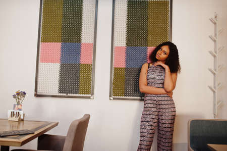 Ð¡harming elegant young african american woman with long curly hair wearing jumpsuit posing at...