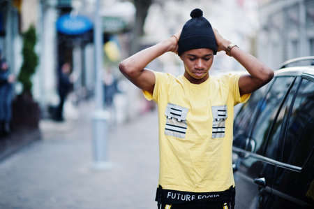 African man wear on black hat posed outdoor against business car.