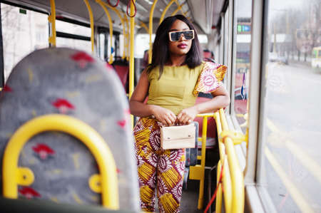 Young stylish african american woman in modern sunglasses riding on a bus.