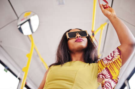 Young stylish african american woman in modern sunglasses riding on a bus.