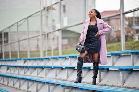Young stylish beautiful african american woman in street at the stadium bleachers, wearing fashion...