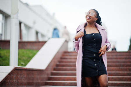 Young stylish beautiful african american woman in street against stairs, wearing fashion outfit...