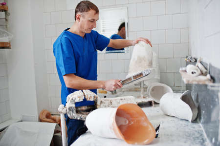 Prosthetist man making prosthetic leg while working in laboratory, makes a model of plaster.
