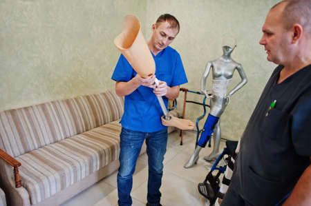 Two prosthetist man workers with prosthetic leg working in laboratory.