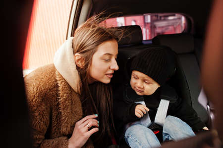 Young mother and child in car. Baby seat on chair. Safety driving concept.