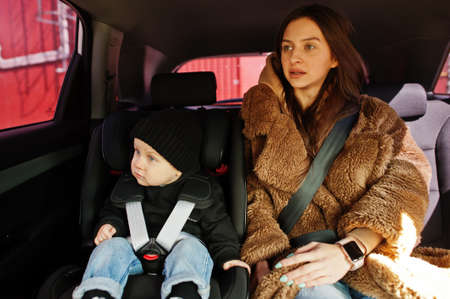 Young mother and child in car. Baby seat on chair. Safety driving concept.