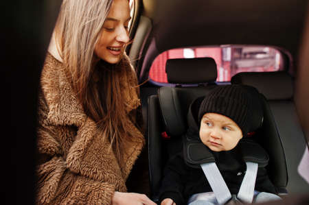 Young mother and child in car. Baby seat on chair. Safety driving concept.