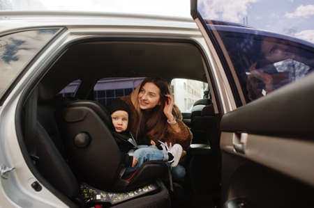 Young mother and child in car. Baby seat on chair. Safety driving concept.
