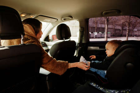 Young mother and child in car. Baby seat on chair. Safety driving concept.