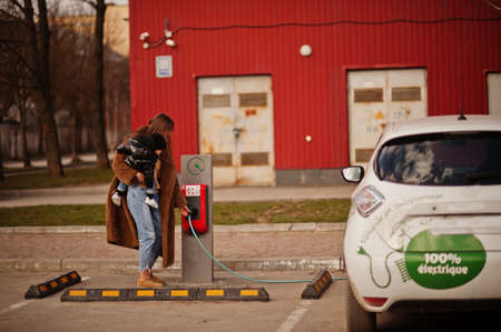 Young mother with child charging electro car at the electric gas station.の写真素材