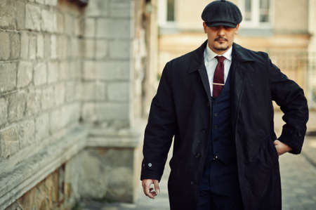 Portrait of retro 1920s english arabian business man wearing dark coat, suit, tie and flat cap.の写真素材