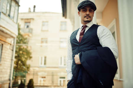 Portrait of retro 1920s english arabian business man wearing dark suit, tie and flat cap.の写真素材