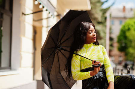 Portrait of young beautiful african american woman holding black umbrella.の写真素材