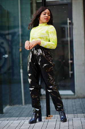 Portrait of young beautiful african american fashion model woman, wear in green top and black shiny...