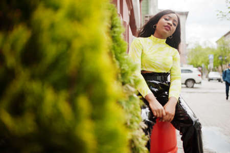 Portrait of young beautiful african american fashion model woman, wear in green top and black shiny...