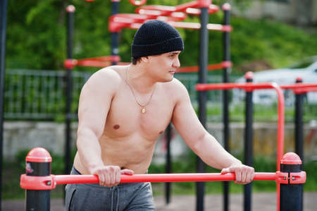 Man arabian sport man torso with hat doing exercises on bars.