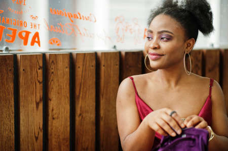 Portrait of a beautiful natural young African woman with afro hair. Black model in red silk dress.の写真素材
