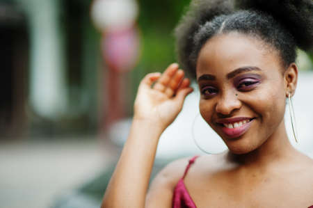 Portrait of a beautiful natural young African woman with afro hair. Black model in red silk dress.