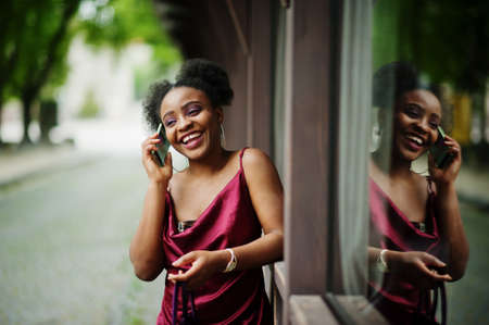 Portrait of a beautiful natural young African woman with afro hair. Black model in red silk dress...