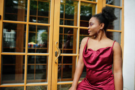 Portrait of a beautiful natural young African woman with afro hair. Black model in red silk dress.の写真素材