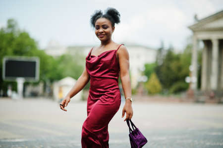 Portrait of a beautiful natural young African woman with afro hair. Black model in red silk dress.の写真素材