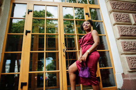 Portrait of a beautiful natural young African woman with afro hair. Black model in red silk dress.の写真素材