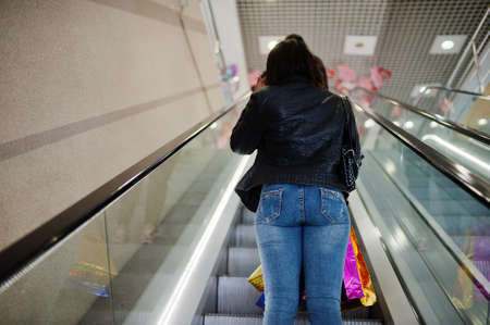 Back of african-american woman walking with colored shopping bags in mall shopping center on...