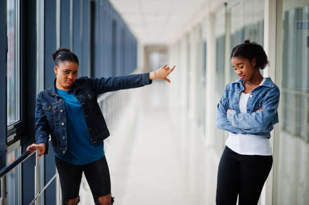 Stay away from me. Two african woman friends in jeans jacket posed indoor together.