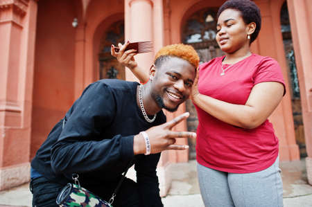 African friend couple having fun outdoor. Girlfriend combs her boyfriend