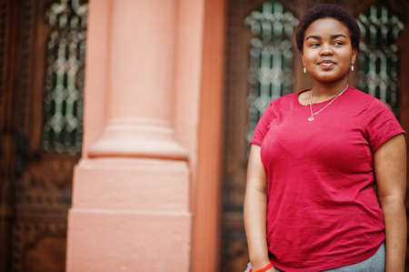 African woman wear red t-shirt posing outdoor.