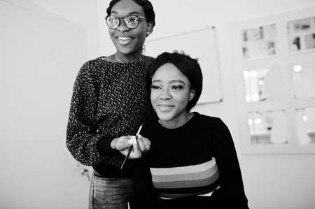 African American woman applying make-up by make-up artist at beauty saloon.の写真素材