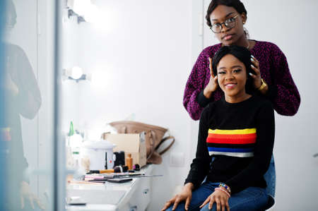 African American woman applying make-up by make-up artist at beauty saloon.の写真素材