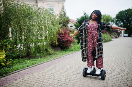 Beautiful african american woman using hoverboard. Black girl on dual wheel self balancing electrical scooter.の写真素材