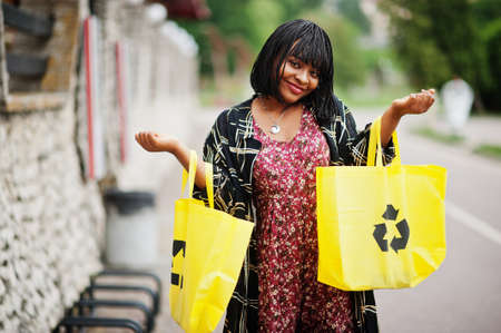 Beautiful african american woman with yellow cloth eco bags recycling symbol.の写真素材