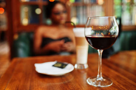 Close up glasses of wine against african american woman at restaurant.の写真素材