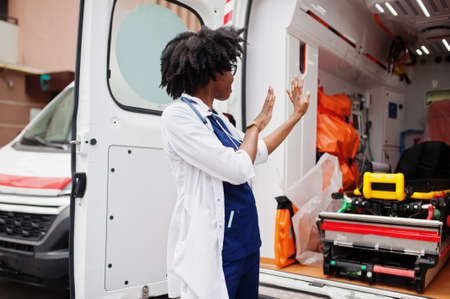 African american female paramedic standing in front of ambulance car.の写真素材