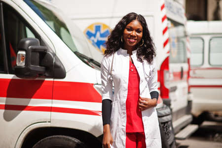 African american female paramedic standing in front of ambulance car.