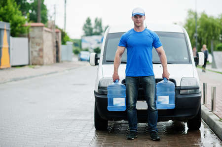 Delivery man in front cargo van delivering bottles of water.の写真素材