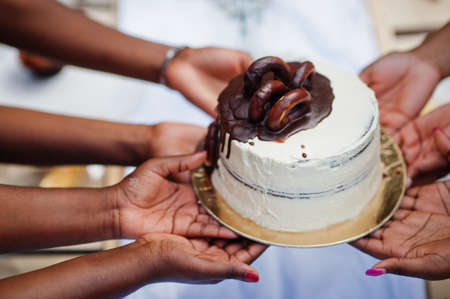 Group of african american girls celebrating birthday party outdoor. Black hands with cake.の写真素材