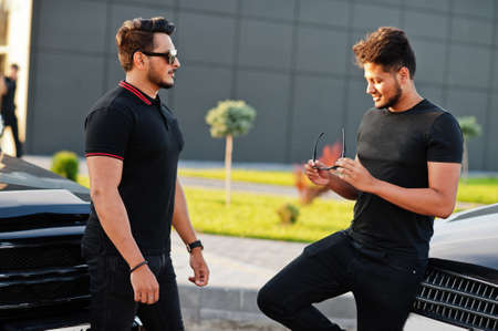Two asian brothers man wear on all black posed near suv cars.