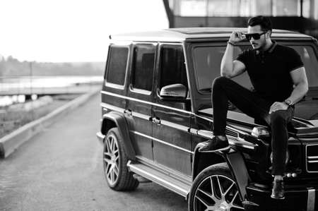 Asian man wear on all black posed near suv car.